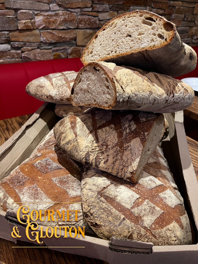 Pain de campagne au levain servi au restaurant Gourmet & Glouton à Chaudes-Aigues, pain artisanal à la croûte croustillante et à la mie aérée, préparé selon la tradition.