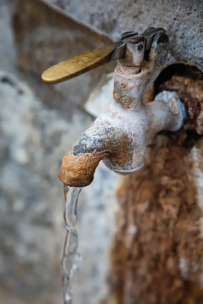 Gros plan d’un robinet ancien avec un filet d’eau à Chaudes-Aigues, dans le centre historique