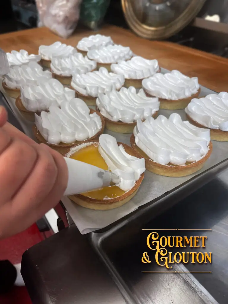 Préparation de tartes au citron meringuées maison chez Gourmet & Glouton, avec application de la meringue à la poche à douille.