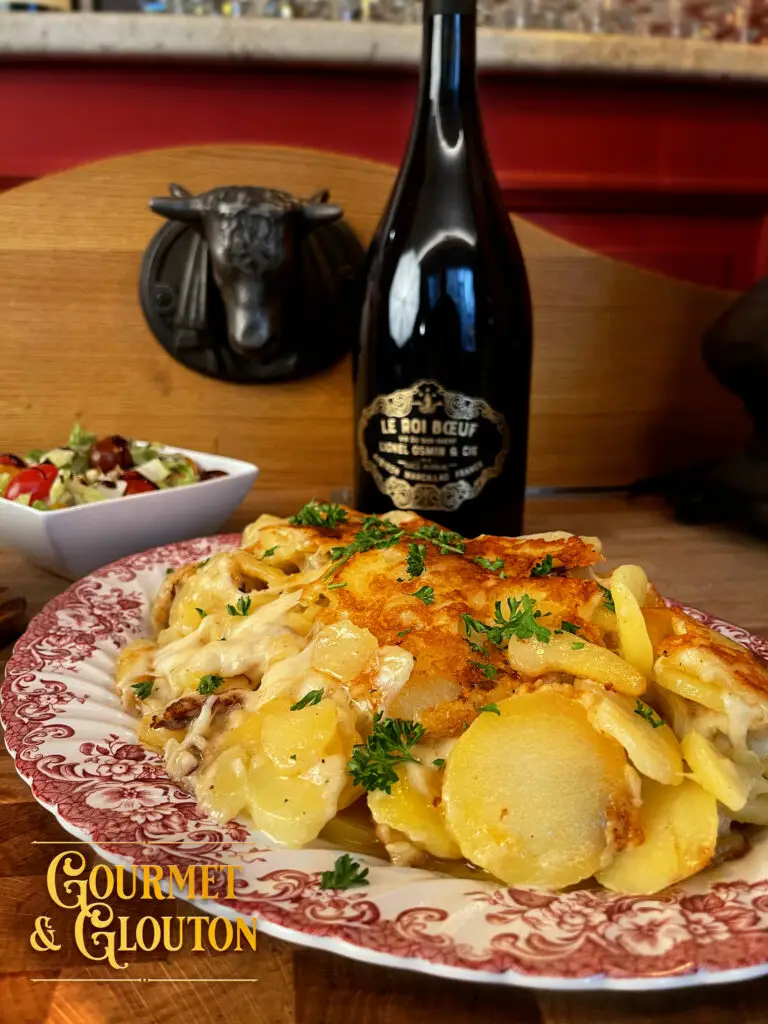 Assiette de truffade auvergnate servie au restaurant Gourmet & Glouton à Chaudes-Aigues, avec salade et bouteille de vin.