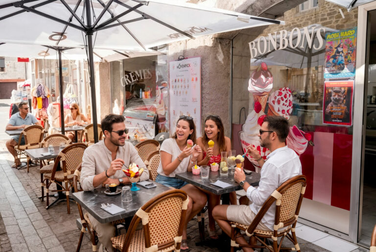Terrasse du glacier Gourmet & Glouton à Chaudes-Aigues, groupe d’amis dégustant des glaces artisanales Mövenpick en centre-ville