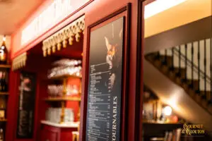 Bouteille « Eaux Thermales de ChaudesAigues » photographiée sur une table du restaurant Gourmet & Glouton, avec une étiquette inspirée d’une affiche ancienne.