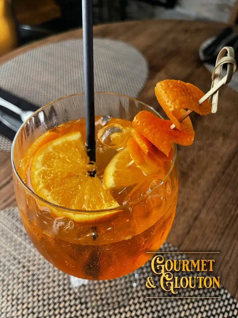 Verre de Spritz servi au restaurant Gourmet & Glouton à Chaudes-Aigues, apéritif à base d’Aperol, de prosecco et d’eau pétillante, symbole de convivialité et de détente.
