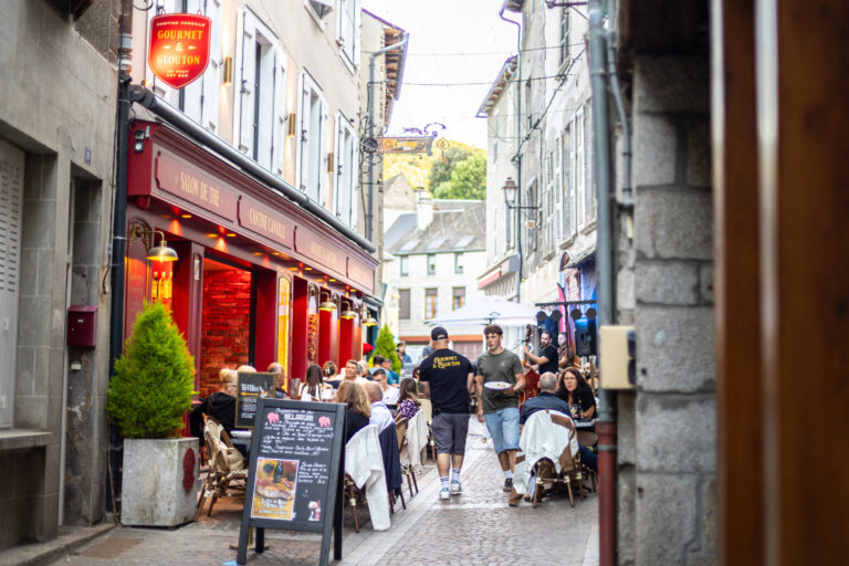 La terrasse ensoleillée du restaurant Gourmet & Glouton à Chaudes-Aigues, remplie de clients