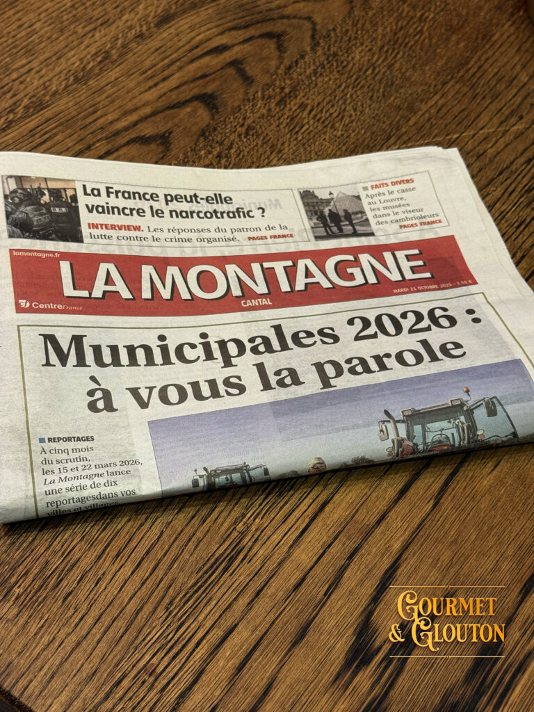 Cyril Cros, créateur de la marque textile BRACO, et le journaliste Yann Bayssat du journal La Montagne échangent autour d’un café au restaurant Gourmet & Glouton, Place des Bougnat à ChaudesAigues, symbole du savoir-faire local entre textile, artisanat et gastronomie auvergnate.
