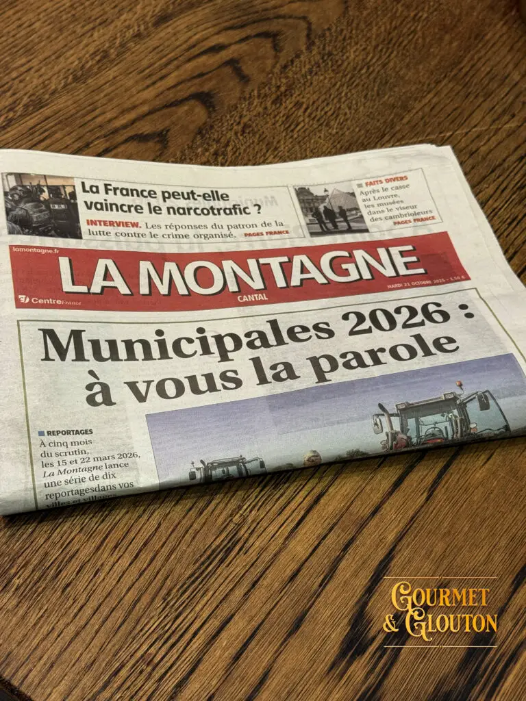 Cyril Cros, créateur de la marque textile BRACO, et le journaliste Yann Bayssat du journal La Montagne échangent autour d’un café au restaurant Gourmet & Glouton, Place des Bougnat à ChaudesAigues, symbole du savoir-faire local entre textile, artisanat et gastronomie auvergnate.