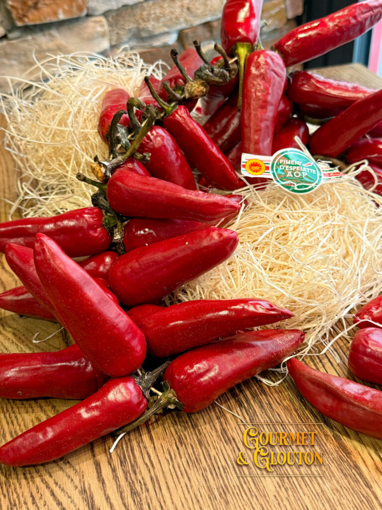 Gros plan sur du piment d’Espelette AOP en poudre et en gousses, mis en scène dans la cuisine du restaurant Gourmet & Glouton à Chaudesaigues