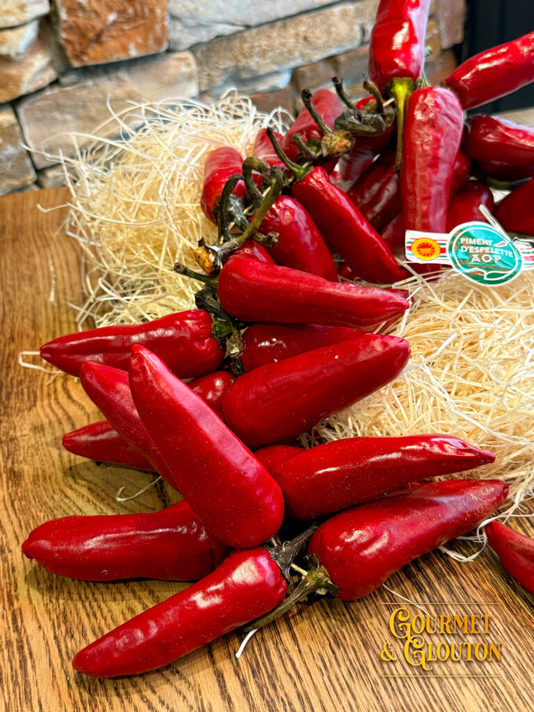 Gros plan sur du piment d’Espelette AOP en poudre et en gousses, mis en scène dans la cuisine du restaurant Gourmet & Glouton à Chaudesaigues