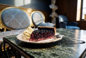Part de tarte aux myrtilles maison servie avec une chantilly généreuse dans le Salon Bleu de Gourmet & Glouton, à Chaudes-Aigues.