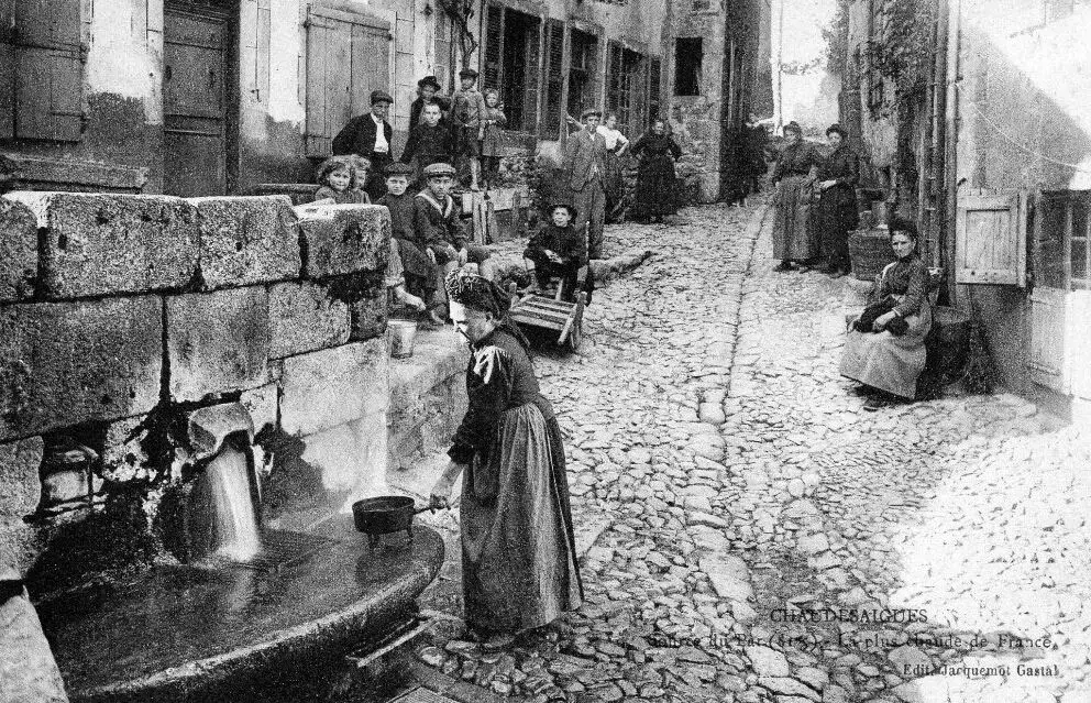 Habitante utilisant l'eau chaude de la Source du Par dans le quartier historique de Chaudes-Aigues au début du XXe siècle.