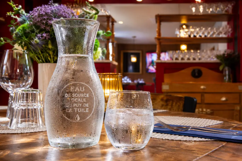 Carafe d'eau de source locale du Puy de la Tuile et verre d'eau fraîche sur une table du restaurant Gourmet & Glouton à Chaudes-Aigues.