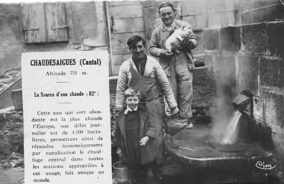 Habitants autour de la Source du Par à Chaudes-Aigues avec panneau explicatif sur l'eau à 82°C et le chauffage géothermique du village.