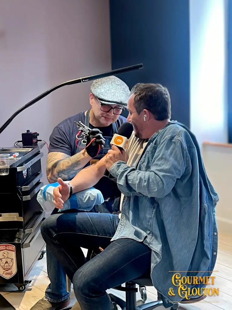 Stéphane Chaudesaigues tatoue Loïc Ballet lors du tournage d'un reportage Télématin à Chaudes-Aigues.
