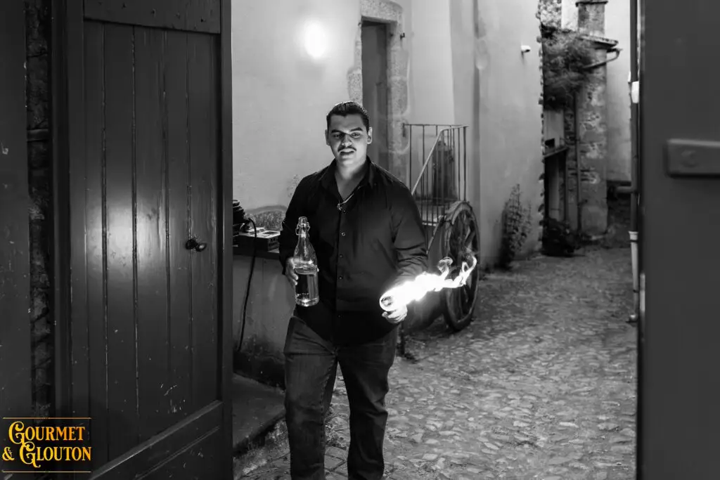 Enzo, alias Petit Dragon, capitaine de cuisine de Gourmet & Glouton, tient une torche enflammée pendant les Terrasses Musicales à Chaudes-Aigues.