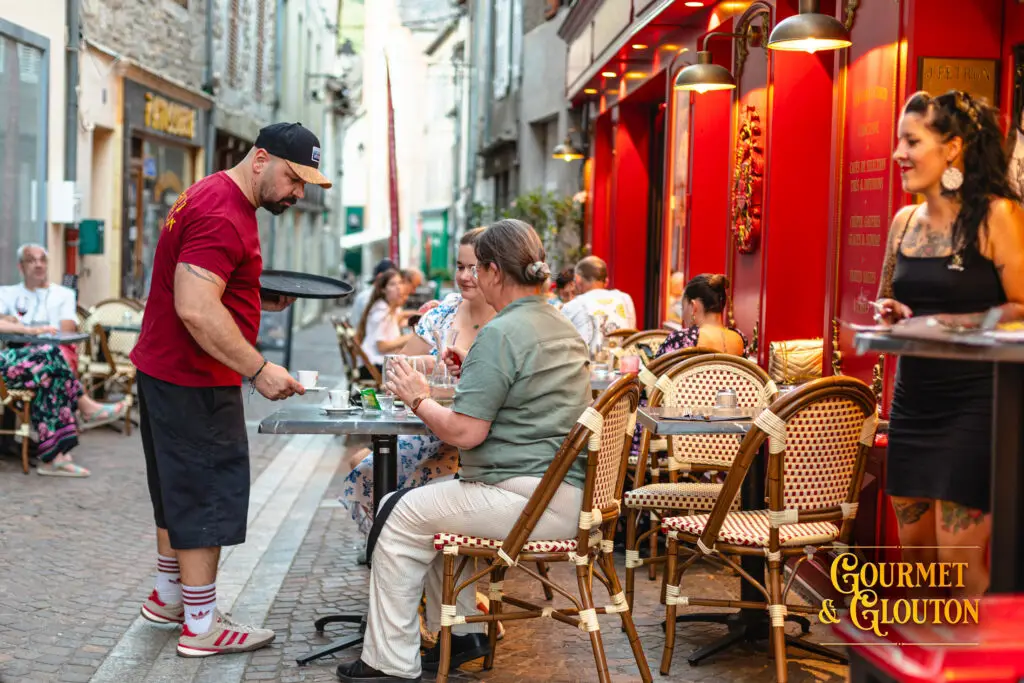 Loïc, surnommé Simon le Torpilleur, assure le service en terrasse chez Gourmet & Glouton pendant les Terrasses Musicales 2026 à Chaudes-Aigues.