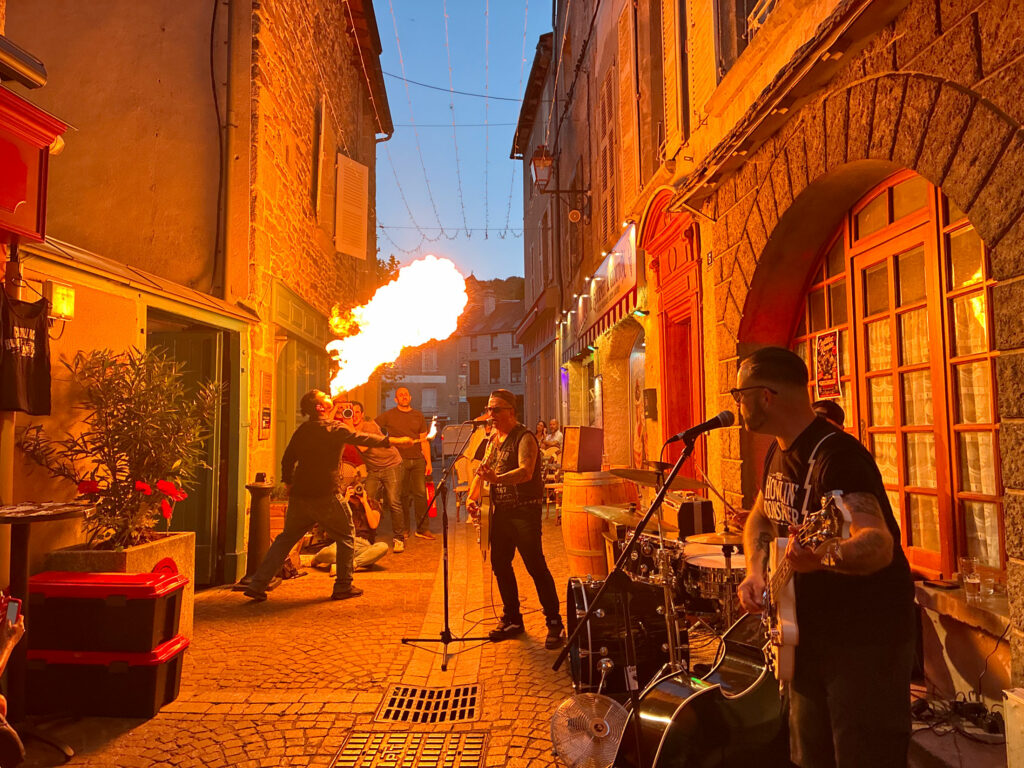 Petit Dragon, capitaine de cuisine de Gourmet & Glouton, crache le feu pendant le concert de Cadillac Rumble aux Terrasses Musicales de Chaudes-Aigues.