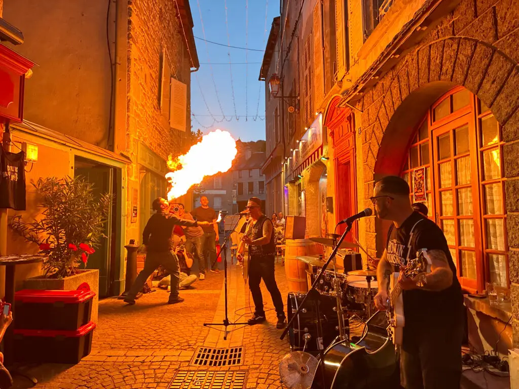 Petit Dragon, capitaine de cuisine de Gourmet & Glouton, crache le feu pendant le concert de Cadillac Rumble aux Terrasses Musicales de Chaudes-Aigues.