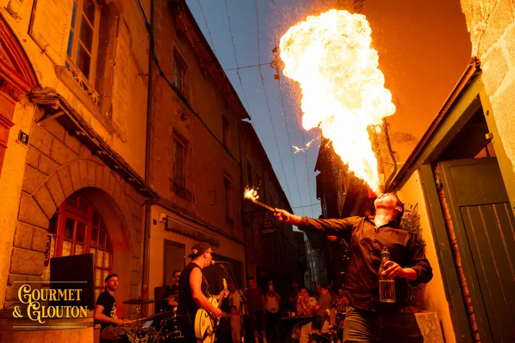 Petit Dragon, capitaine de cuisine de Gourmet & Glouton, crache le feu pendant une soirée des Terrasses Musicales 2026 à Chaudes-Aigues.