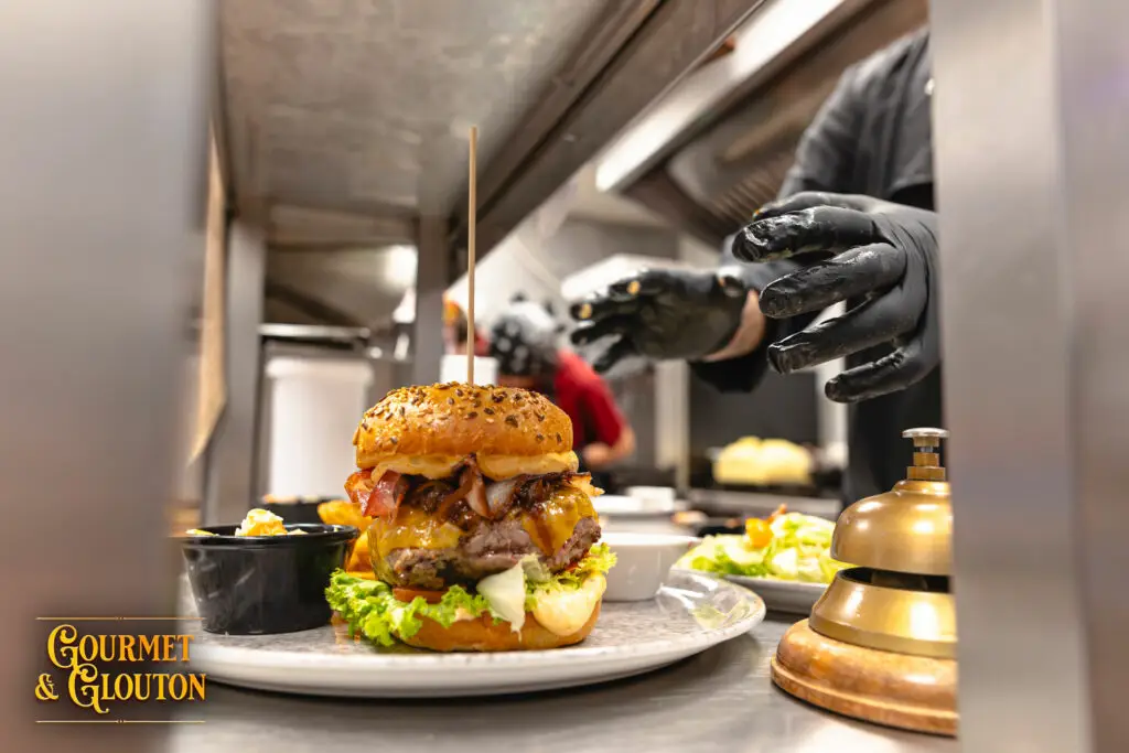 Préparation du Double G, burger d’Aubrac de Gourmet & Glouton, en cuisine pendant le service des Terrasses Musicales à Chaudes-Aigues.