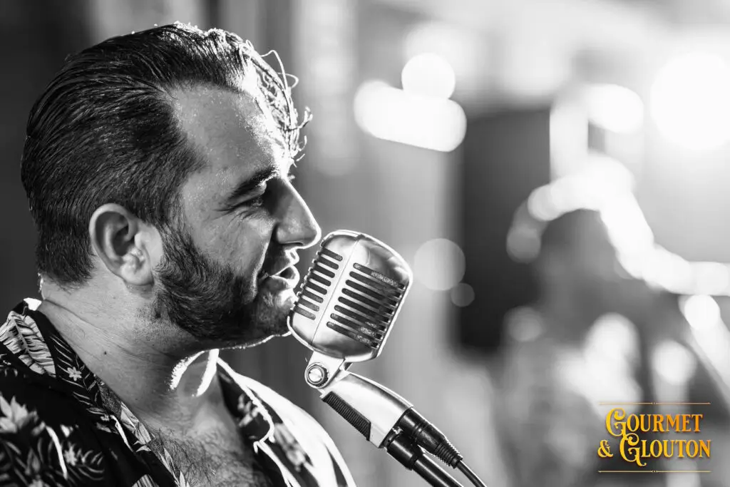 Chanteur de Wild Karma au micro pendant les Terrasses Musicales de Chaudes-Aigues.