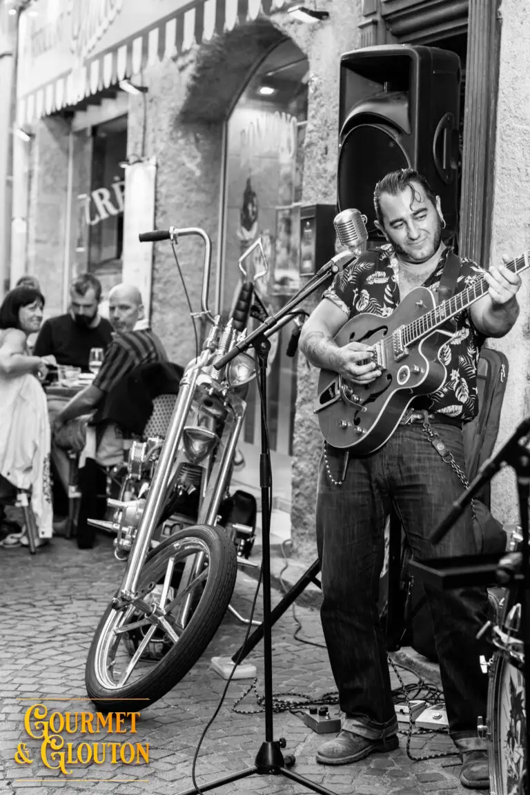 Guitariste de Wild Karma devant sa moto pendant les Terrasses Musicales de Chaudes-Aigues.